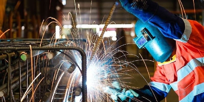 کارگر در حال جوشکاری میلگردهای ساختمان